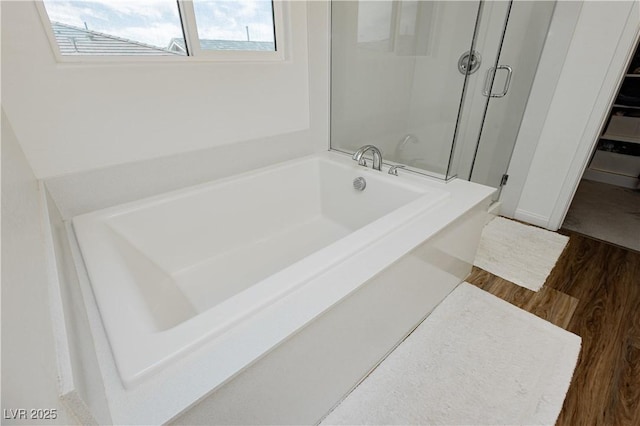 bathroom featuring a garden tub, a shower stall, and wood finished floors