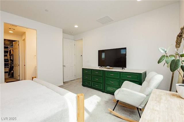 bedroom with light colored carpet, visible vents, a spacious closet, and recessed lighting