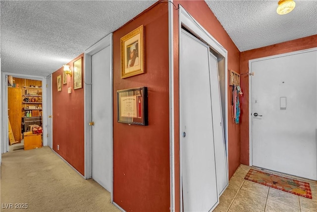 corridor with light tile patterned flooring, light carpet, and a textured ceiling