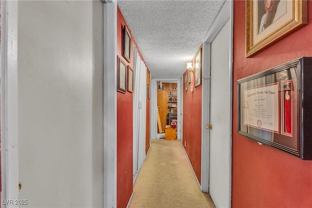 corridor featuring light colored carpet and a textured ceiling