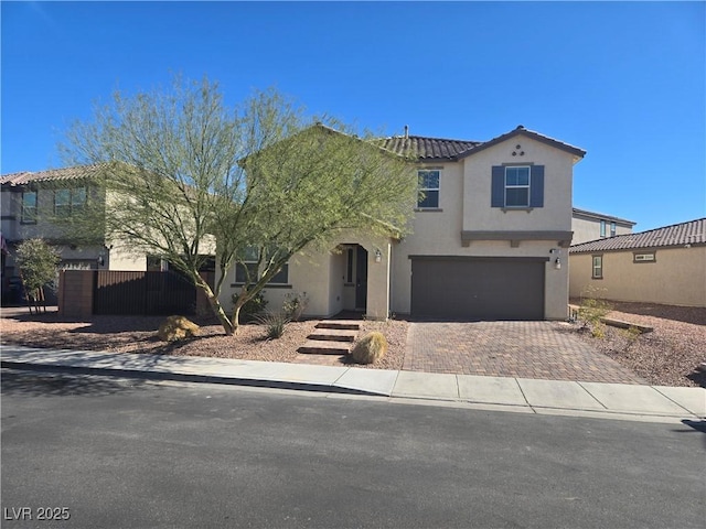 view of front of home with an attached garage, fence, a tiled roof, decorative driveway, and stucco siding