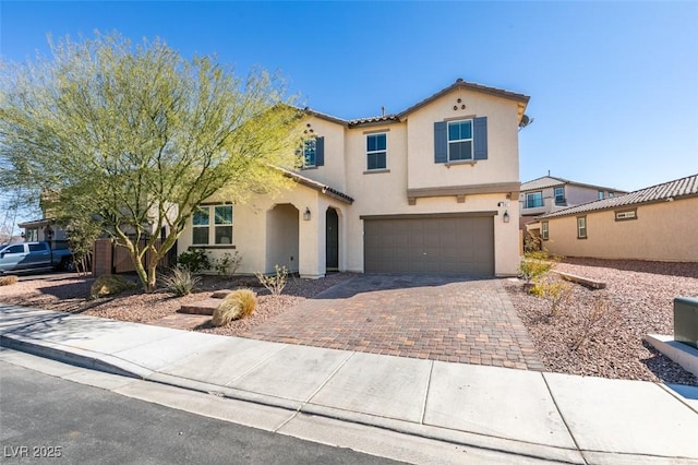 mediterranean / spanish house with a garage, a tiled roof, decorative driveway, and stucco siding