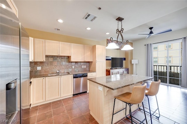 kitchen with stainless steel appliances, a kitchen island, visible vents, light stone countertops, and decorative light fixtures