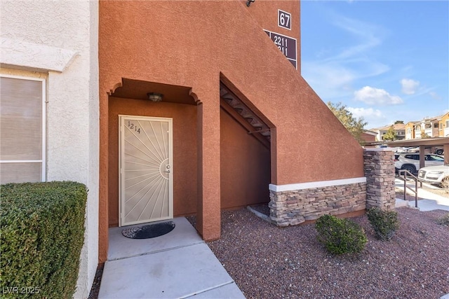 property entrance featuring stone siding and stucco siding