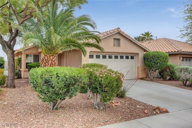 mediterranean / spanish-style house featuring a garage, concrete driveway, a tile roof, and stucco siding