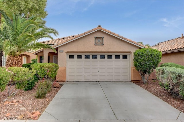 view of front of house with driveway, an attached garage, a tiled roof, and stucco siding