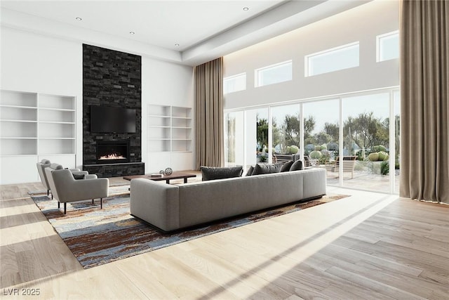 living area featuring a towering ceiling, built in shelves, a fireplace, and wood finished floors