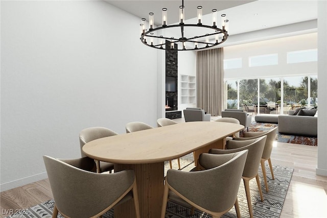 dining space with baseboards, light wood finished floors, a towering ceiling, and an inviting chandelier