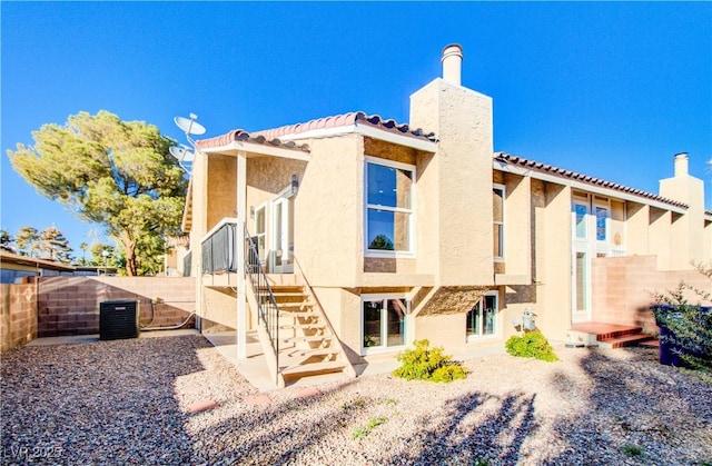 rear view of house featuring a fenced backyard, a chimney, and stucco siding