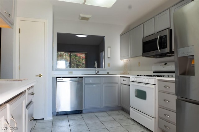 kitchen with light countertops, appliances with stainless steel finishes, light tile patterned flooring, and a sink