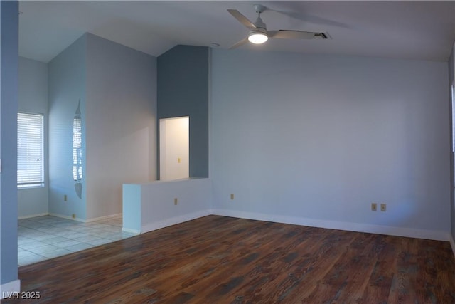 unfurnished room featuring a ceiling fan, vaulted ceiling, light wood-style floors, and baseboards