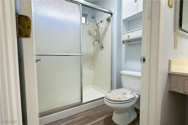 full bathroom featuring toilet, a shower stall, wood finished floors, and vanity