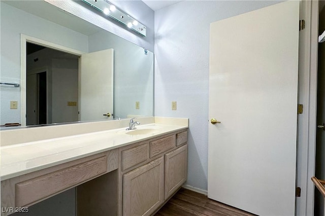 bathroom featuring baseboards, wood finished floors, and vanity