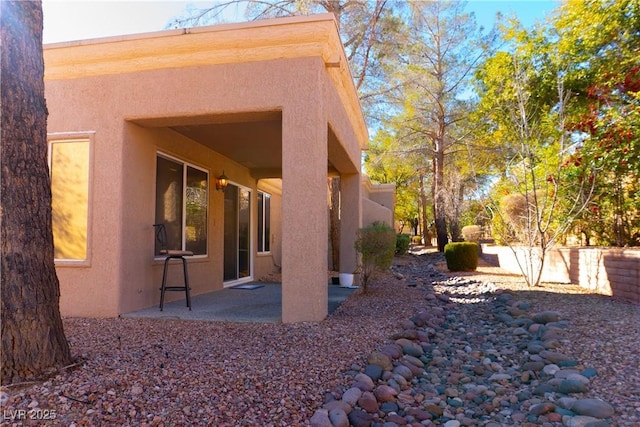 rear view of house featuring a patio, fence, and stucco siding