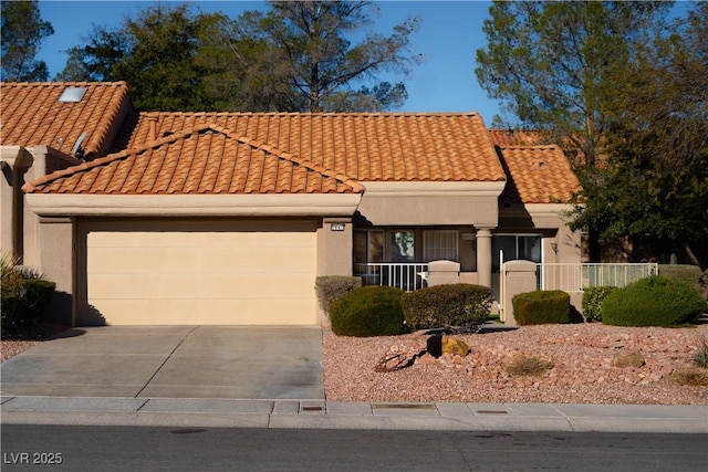 view of front of property with an attached garage, fence, a tile roof, concrete driveway, and stucco siding