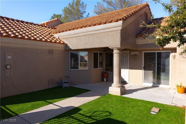 exterior space featuring a patio area, a lawn, and stucco siding