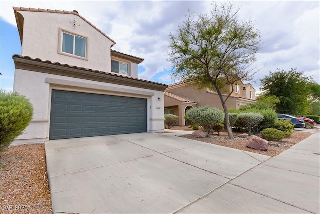 mediterranean / spanish home featuring a garage, driveway, a tiled roof, and stucco siding