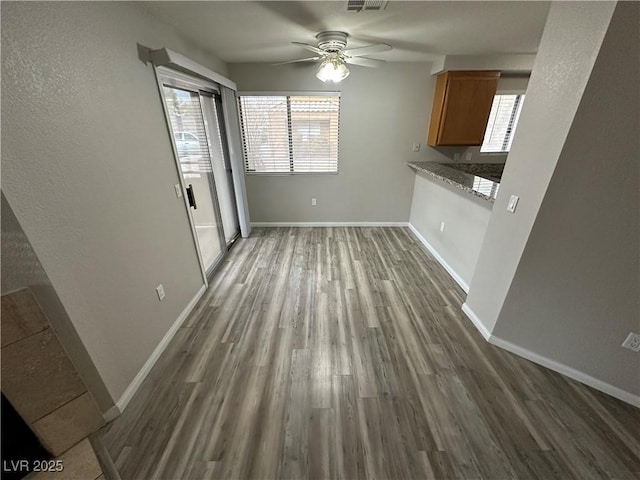 unfurnished dining area featuring a healthy amount of sunlight, dark wood finished floors, and baseboards