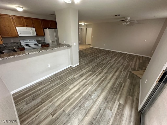 kitchen with brown cabinetry, white appliances, visible vents, and a peninsula