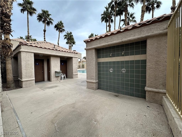 view of side of property featuring a tile roof and stucco siding