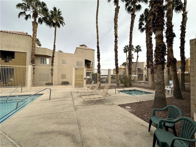 pool featuring a hot tub, fence, and a patio