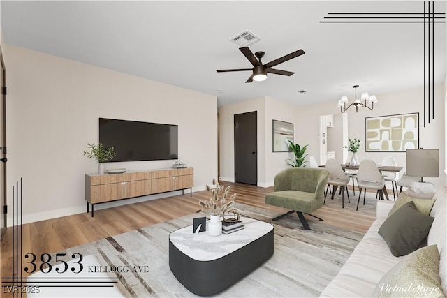 living room featuring ceiling fan with notable chandelier, visible vents, baseboards, and wood finished floors