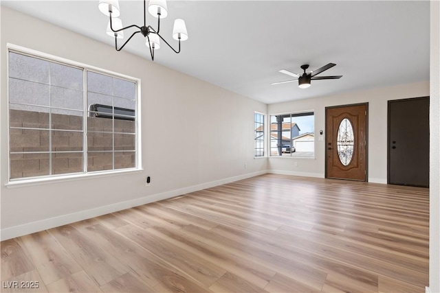 interior space with ceiling fan with notable chandelier, light wood-style flooring, and baseboards