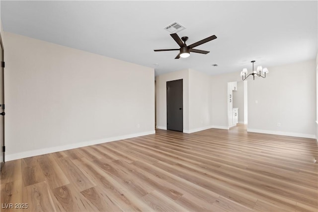 empty room featuring light wood finished floors, baseboards, visible vents, and ceiling fan with notable chandelier