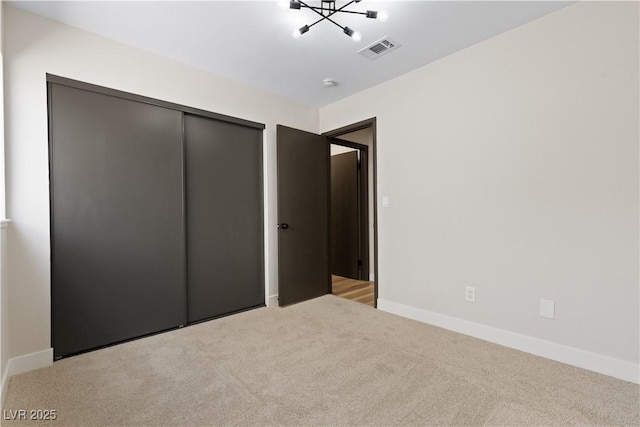 unfurnished bedroom featuring light carpet, baseboards, visible vents, and a closet