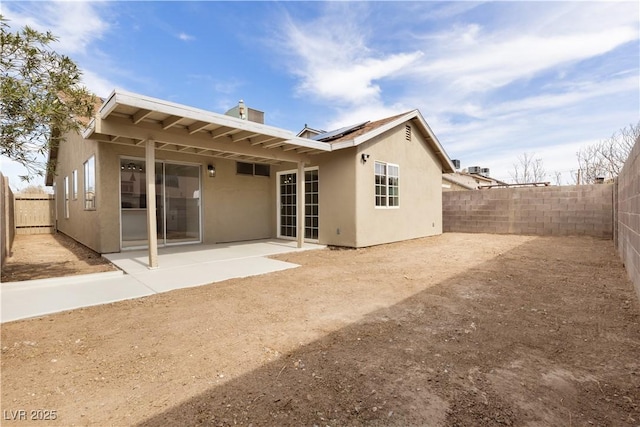 back of property with a patio, roof mounted solar panels, a fenced backyard, and stucco siding