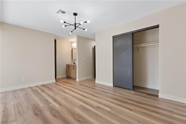 unfurnished bedroom with light wood finished floors, baseboards, visible vents, a notable chandelier, and a closet