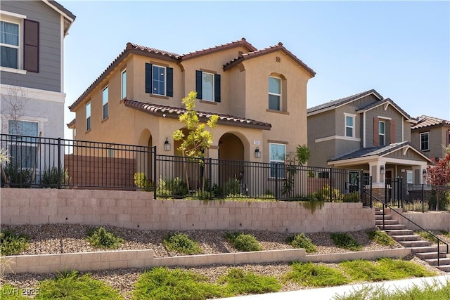 view of front of property featuring a fenced front yard, a tiled roof, stairway, and stucco siding