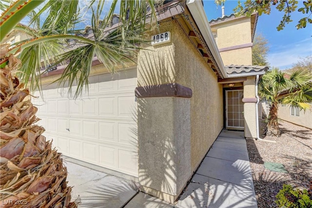 exterior space featuring a garage, a tile roof, and stucco siding