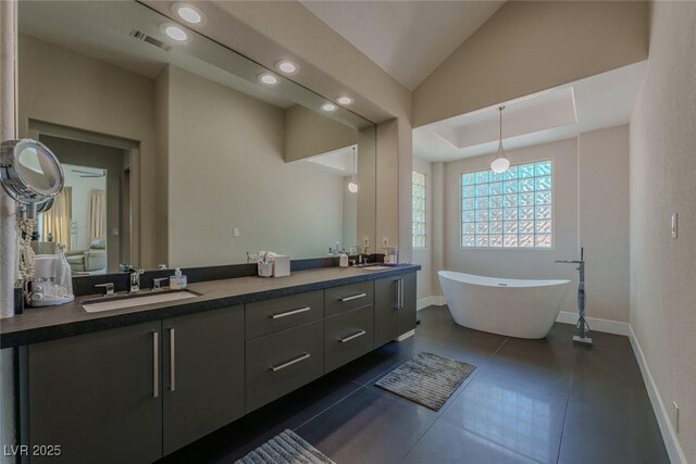 full bath featuring double vanity, a freestanding bath, visible vents, and a sink