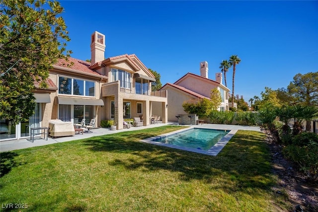 back of house featuring a patio, a balcony, a lawn, a fenced in pool, and a chimney