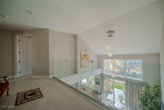 hallway featuring vaulted ceiling, carpet, and baseboards