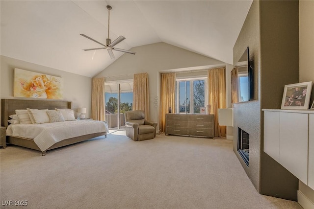 bedroom featuring access to exterior, a ceiling fan, a glass covered fireplace, light carpet, and high vaulted ceiling