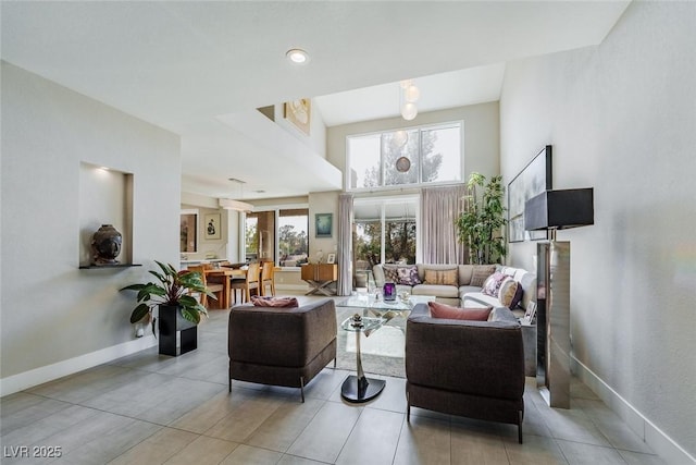 living room featuring a towering ceiling, plenty of natural light, and baseboards