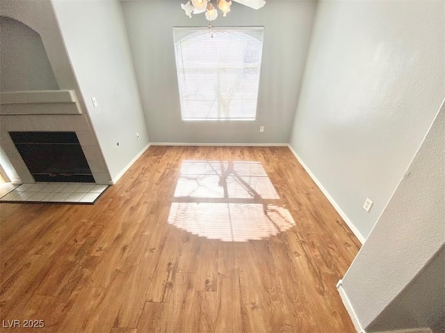 unfurnished dining area featuring a fireplace, wood finished floors, and baseboards