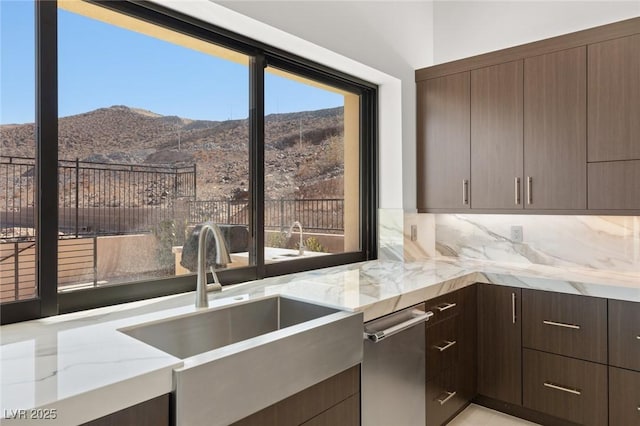 kitchen featuring tasteful backsplash, a mountain view, dark brown cabinetry, and light stone countertops