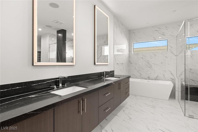 bathroom featuring marble finish floor, double vanity, a soaking tub, and a sink