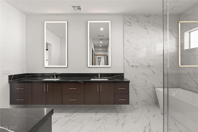 full bath with a sink, visible vents, marble finish floor, a soaking tub, and double vanity