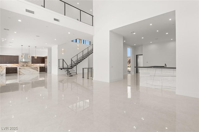 interior space featuring marble finish floor, visible vents, stairway, and a high ceiling