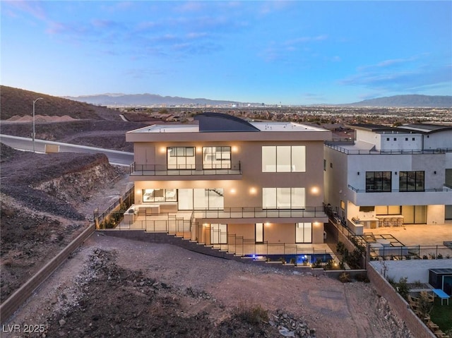 rear view of property featuring stucco siding, a mountain view, and fence