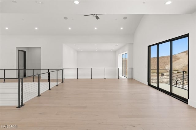 unfurnished room with light wood-style flooring, a mountain view, a wealth of natural light, and recessed lighting