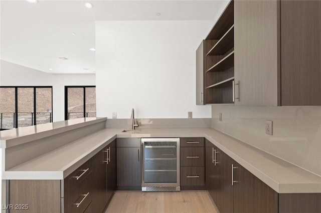 kitchen featuring beverage cooler, light countertops, a peninsula, and open shelves