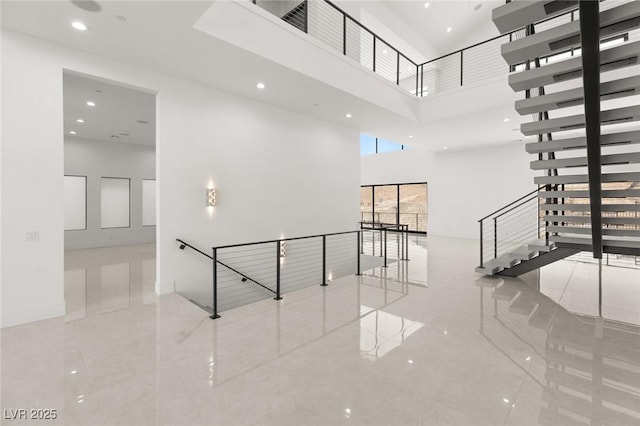 interior space featuring a high ceiling, baseboards, and recessed lighting