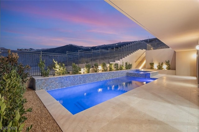 view of pool featuring a pool with connected hot tub, a patio area, fence, and a mountain view