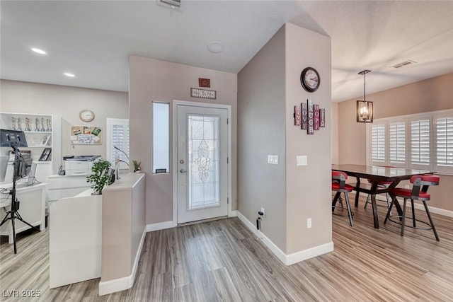 entrance foyer with light wood-type flooring, a healthy amount of sunlight, visible vents, and baseboards