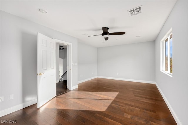 empty room with a ceiling fan, baseboards, visible vents, and dark wood-style flooring